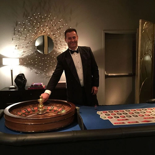 Roulette dealer in a tuxedo ready to deal at a Corporate Holiday Party.